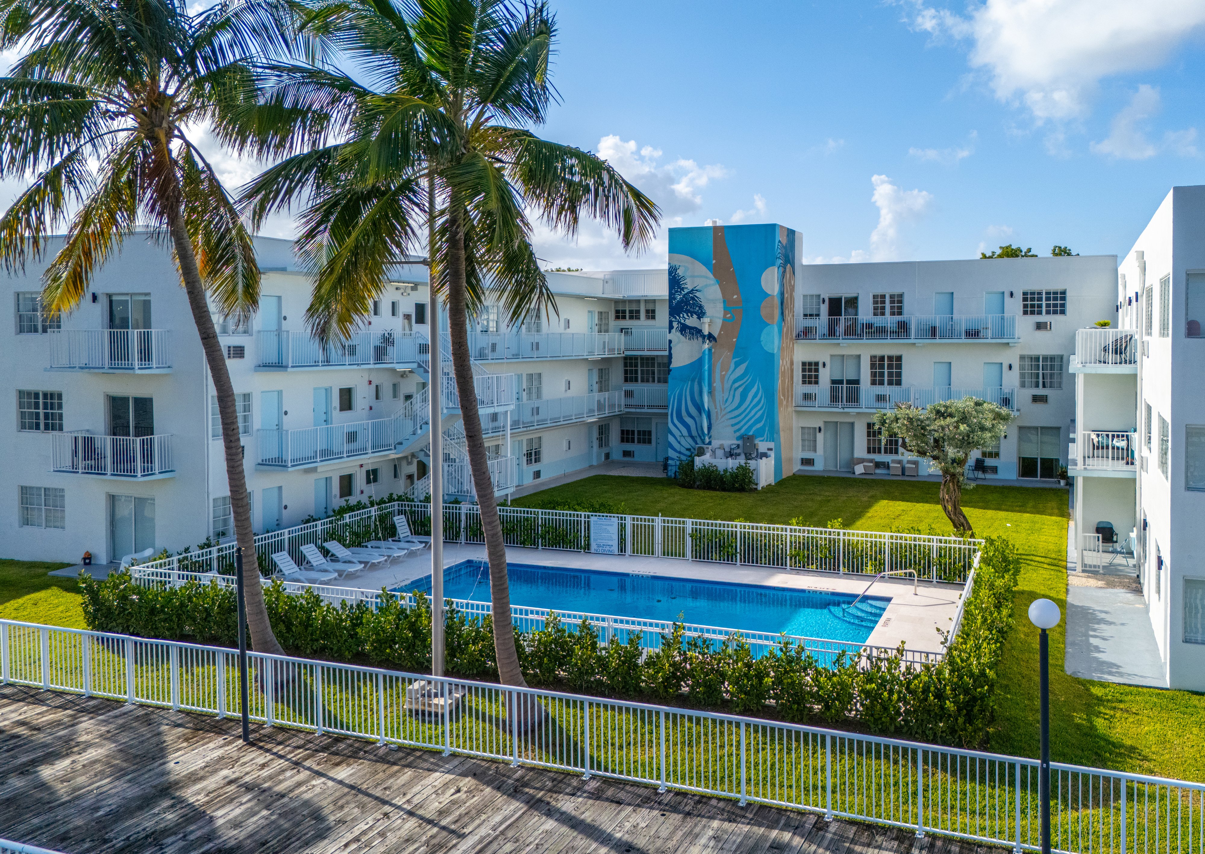 A pool surrounded by a fence and palm trees.